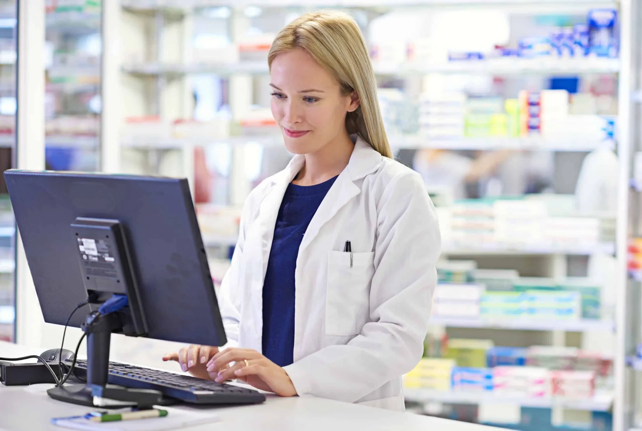 Pharmacist reviewing a prescription record at the pharmacy computer